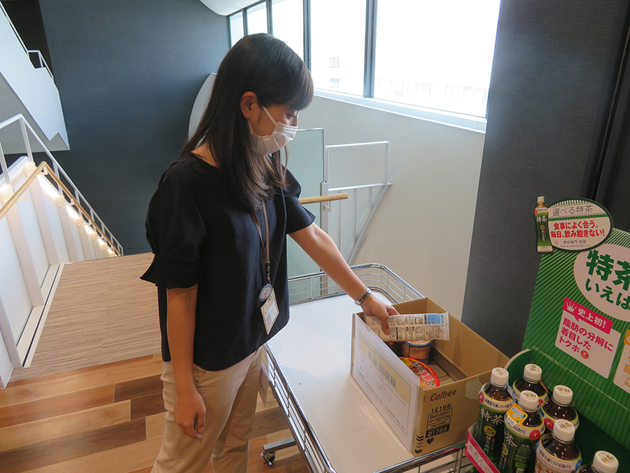 Photo:A company member placing food donations into a collection box at a company building